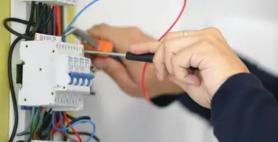 Electrician installing and adjusting circuit breakers in an electrical panel in Grand Rapids, MI