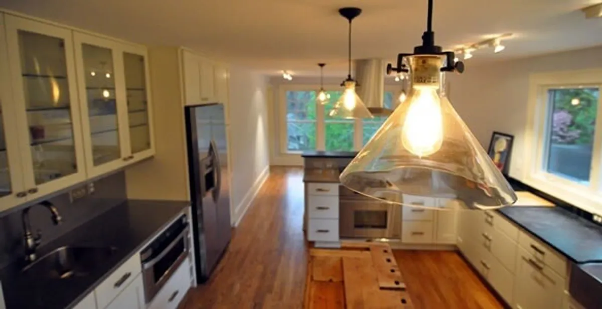 Residential electrician installing modern indoor light fixture in a home in Grand Rapids, MI