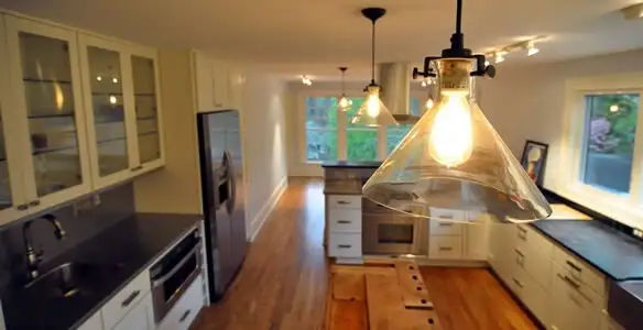 Residential electrician installing modern indoor light fixture in a home in Grand Rapids, MI