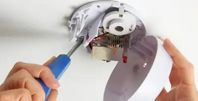 Certified technician wiring smoke detector during installation in Grand Rapids, MI